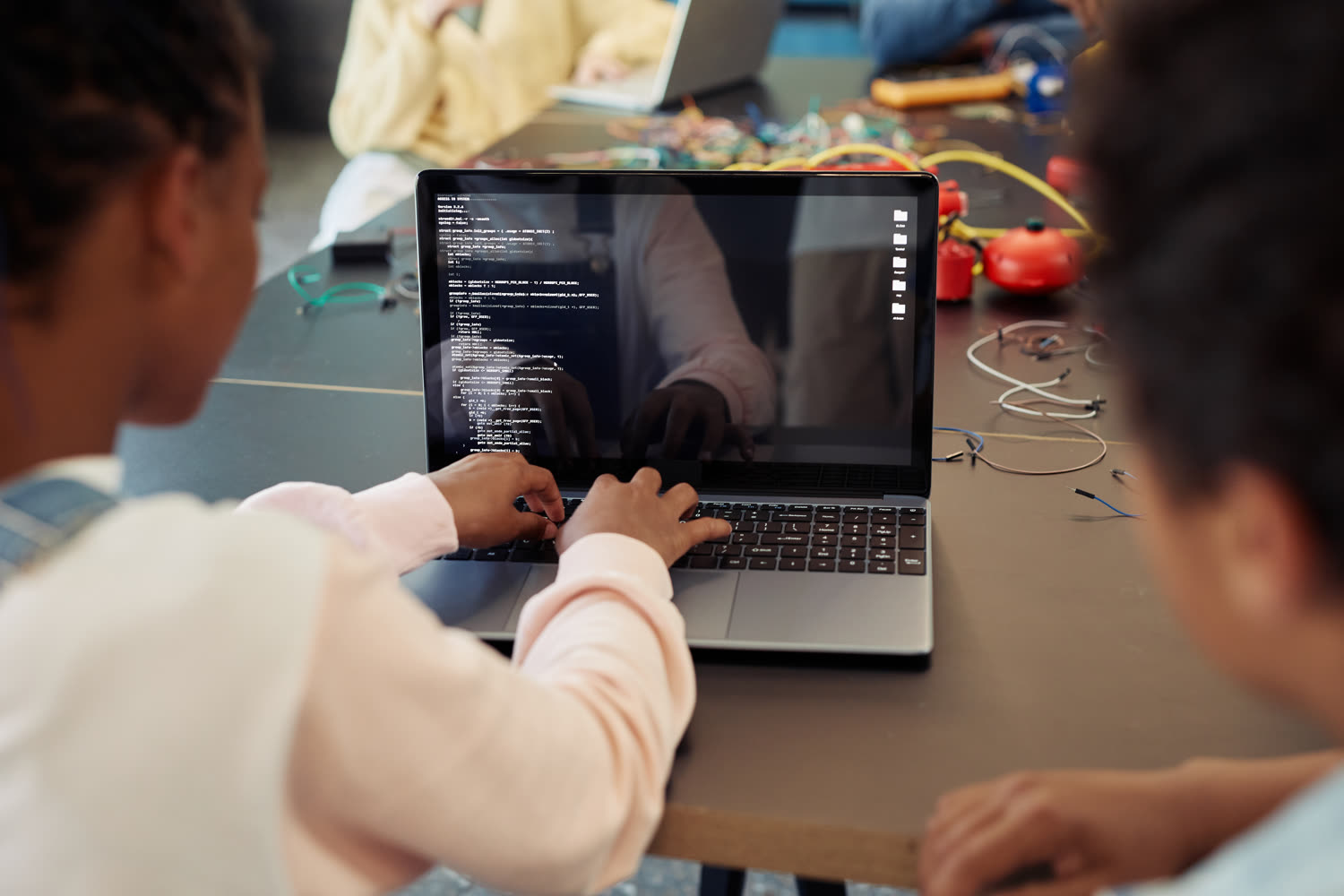 Students collaborating on a coding project on a laptop